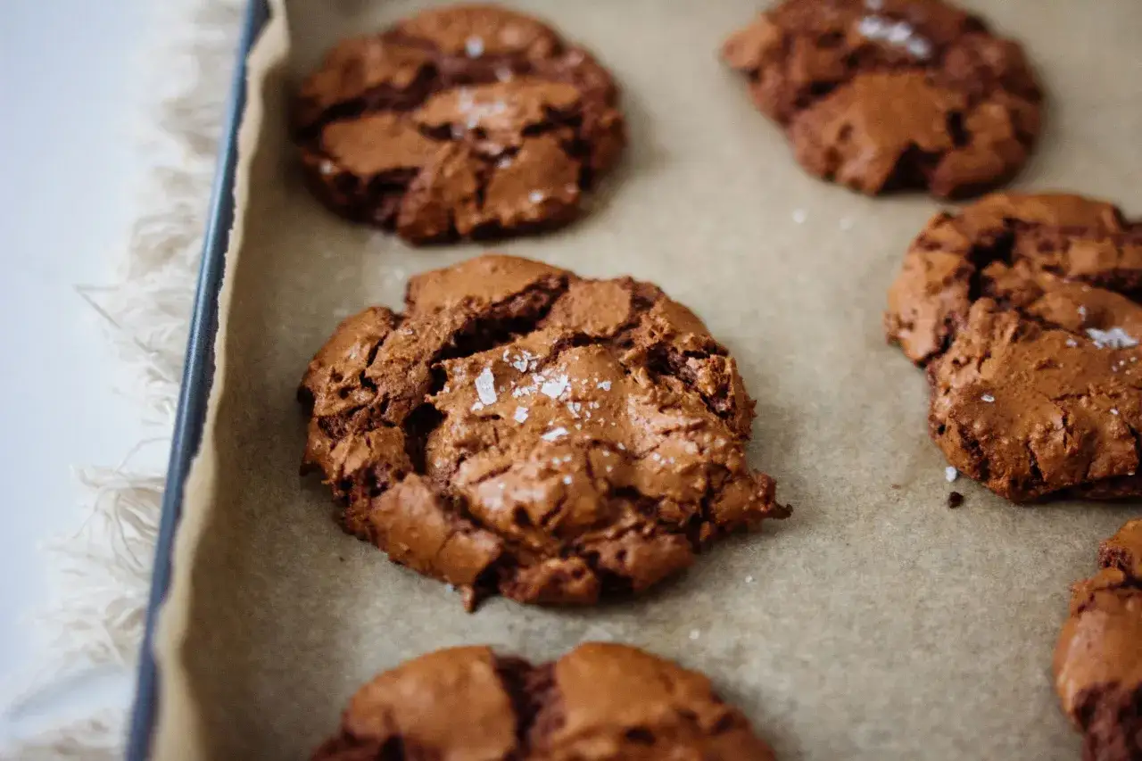 Saftige triple chocolate cookies, bestreut mit Meersalz, liegen auf Backpapier.