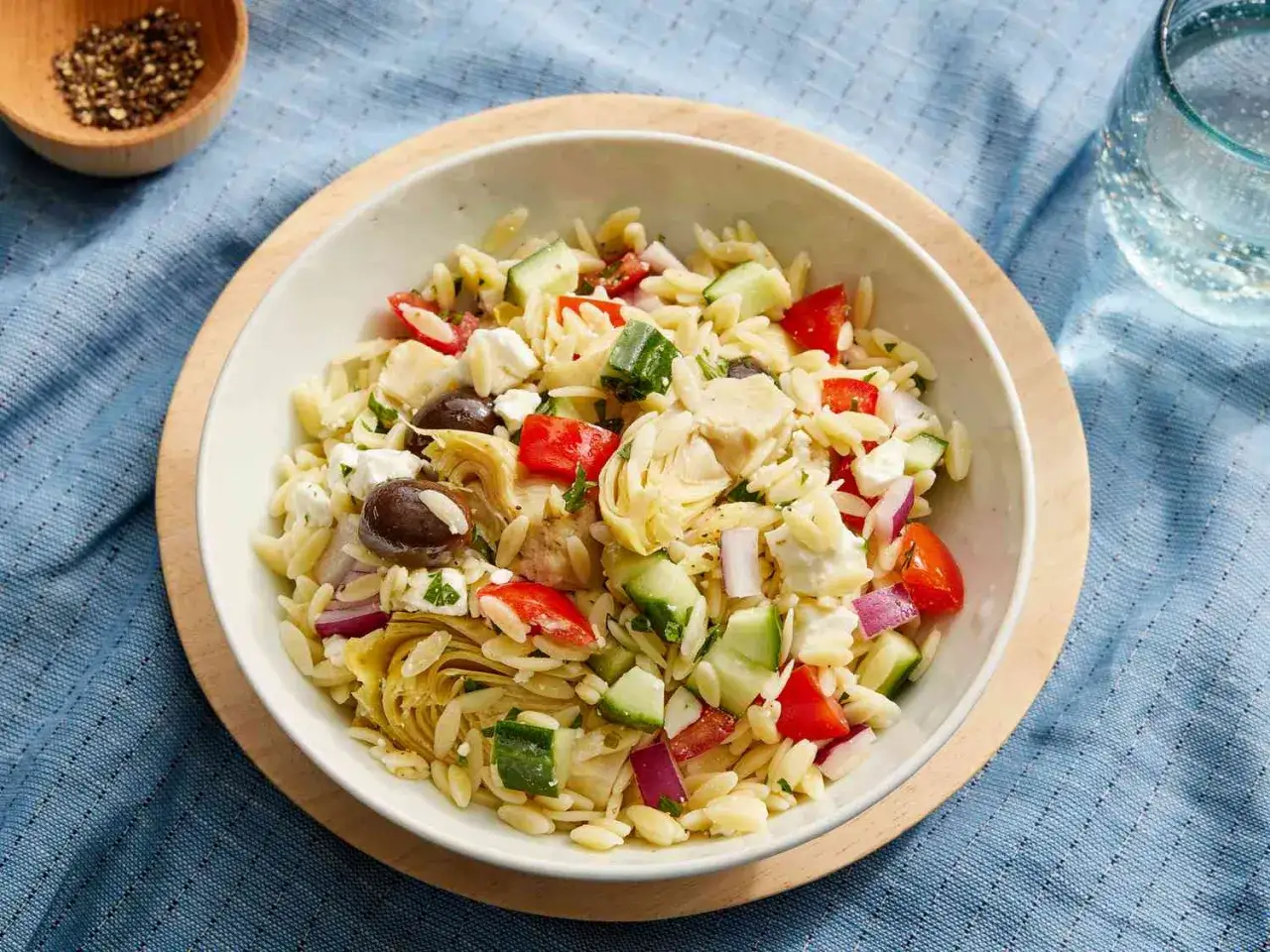 Sch&uuml;ssel mit einem schnellen Kritharaki-Salat, gef&uuml;llt mit Orzo-Nudeln, Artischocken, Gurken, Tomaten, roten Zwiebeln, Oliven und Feta.