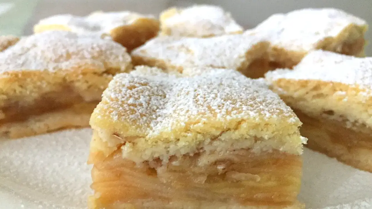Saftige St&uuml;cke von gedecktem Apfelkuchen, best&auml;ubt mit Puderzucker, laden zum Genuss ein.