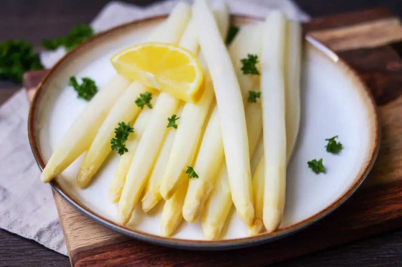 Frischer wei&szlig;er Spargel, perfekt gekocht, garniert mit Petersilie und einer Zitronenspalte auf einem Teller. Ein Genuss, wenn Spargel Saison hat.