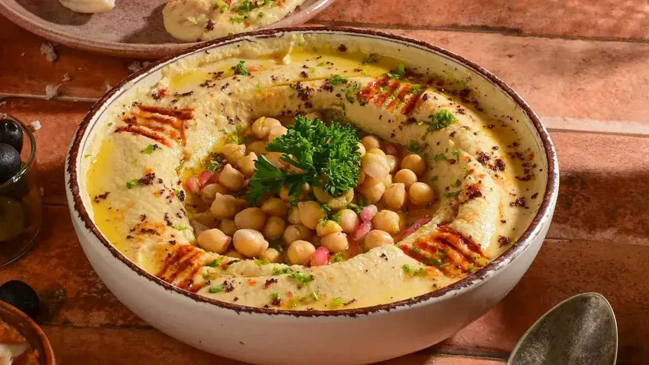 Cremiger Hummus mit Kichererbsen, Granatapfelkernen und Petersilie, garniert mit Oliven&ouml;l und Paprikapulver. Tolle Rezepte f&uuml;r jeden Anlass!
