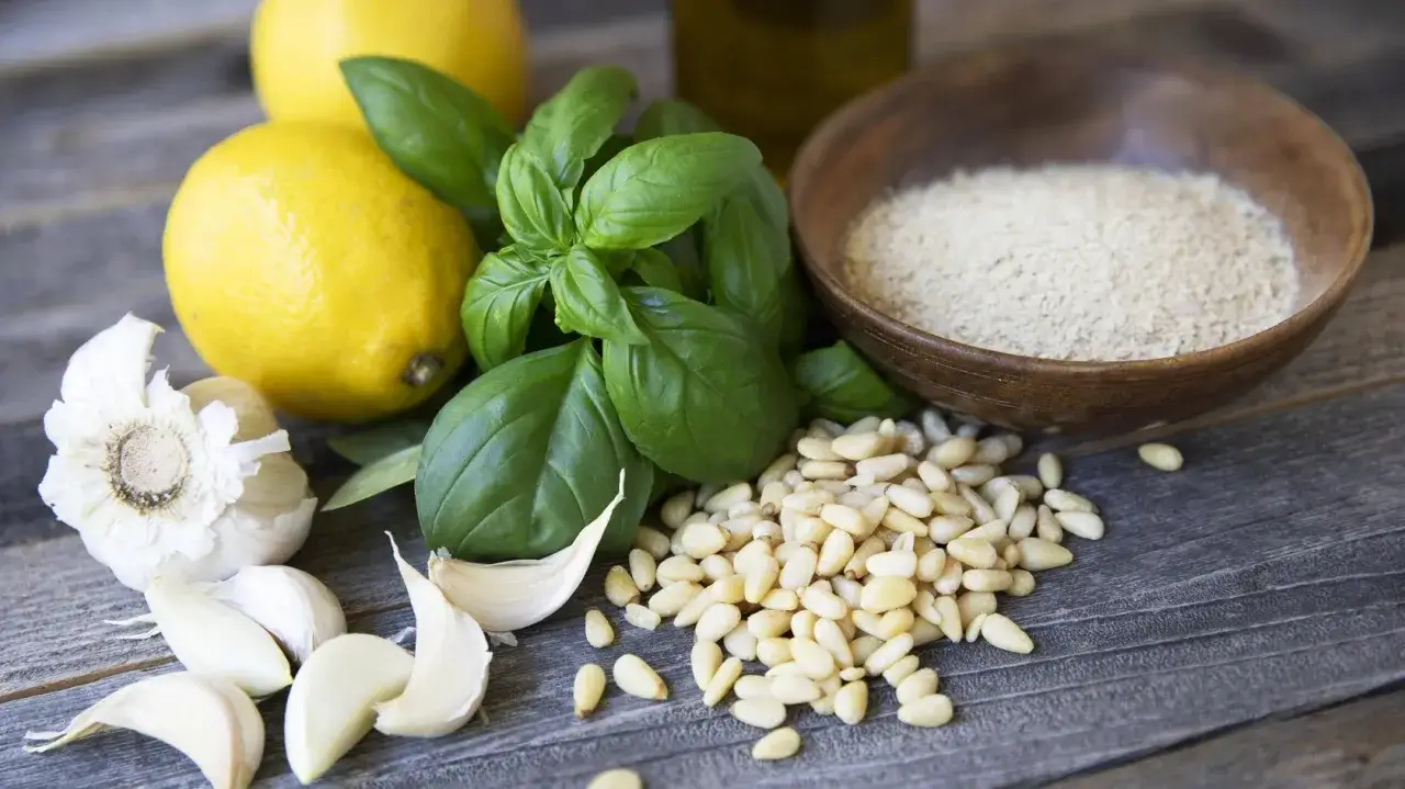 Zutaten f&uuml;r Pesto: Pinienkerne, Knoblauch, Basilikum, Zitrone und eine Schale mit dem hefeflocken ersatz.
