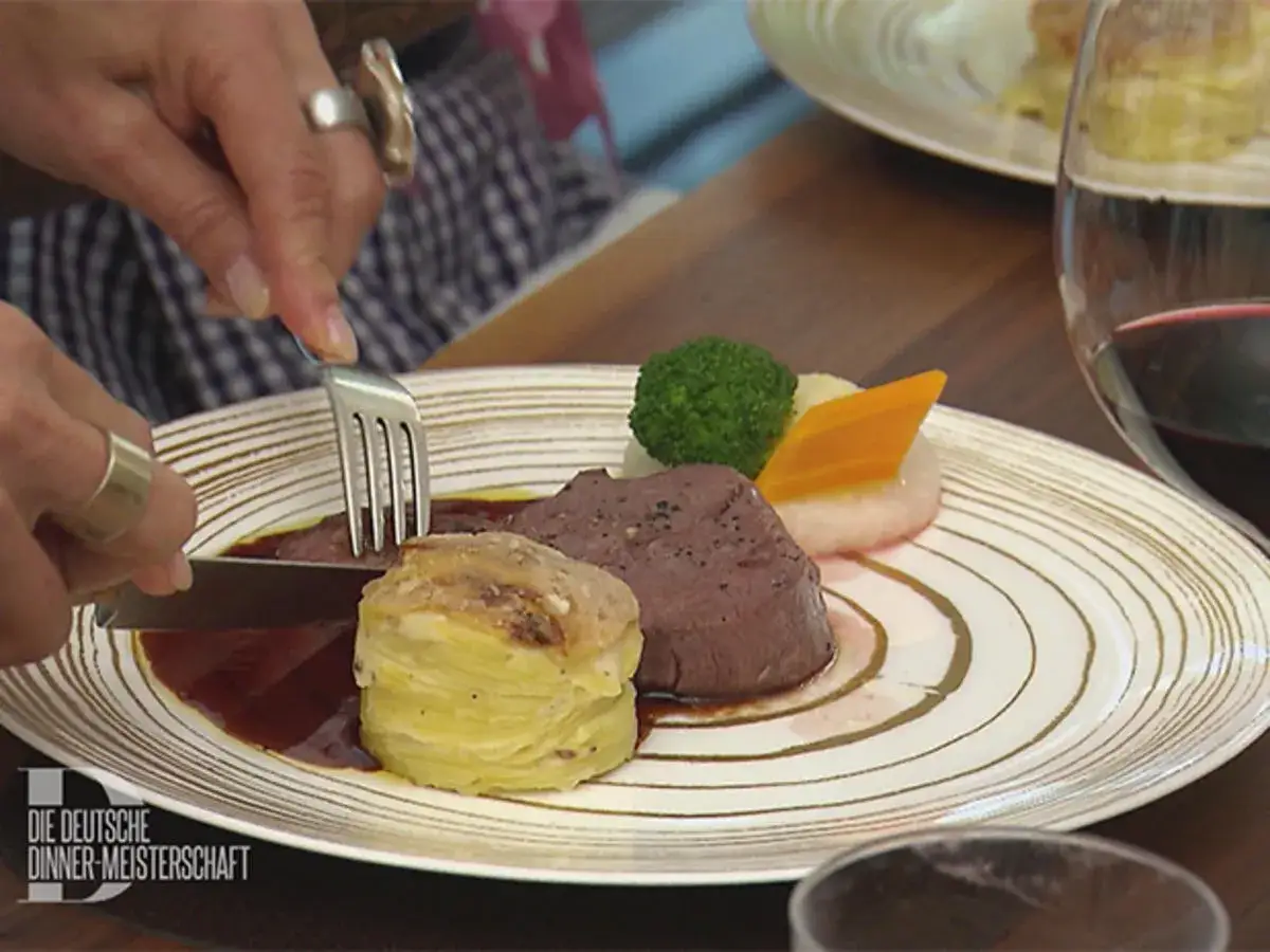 Ein zartes St&uuml;ck Fleisch mit Gem&uuml;se und einem runden Kartoffelgratin als Hauptspeise zu Kartoffelgratin.