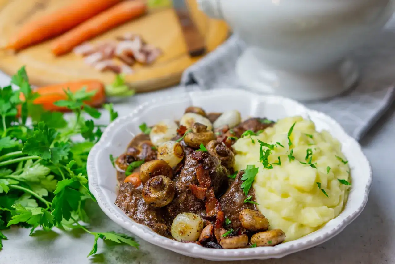 Boeuf Bourguignon mit cremigen Kartoffelp&uuml;ree als Beilage, garniert mit frischer Petersilie.