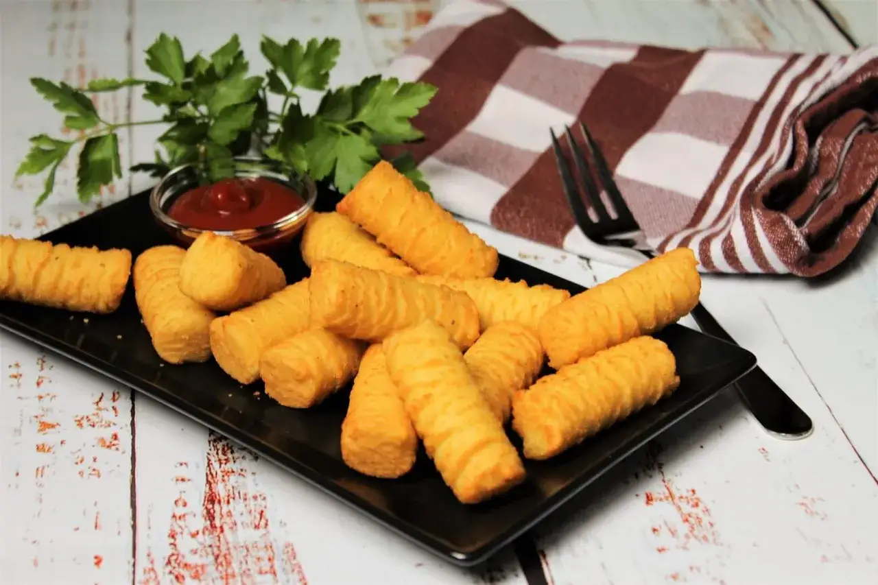 Goldbraune Kroketten, frisch zubereitet, liegen auf einem schwarzen Teller. Dazu gibt es Ketchup und frische Petersilie. Perfekt, um Kroketten selber machen zu lernen!