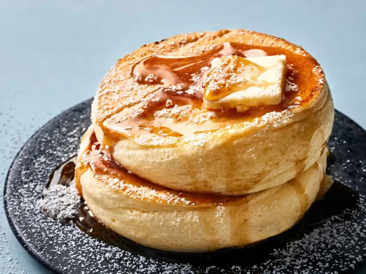 Fluffige japanische Pancakes, gestapelt und mit Puderzucker, Butter und Sirup betr&auml;ufelt. Ein Genuss f&uuml;r die Sinne!