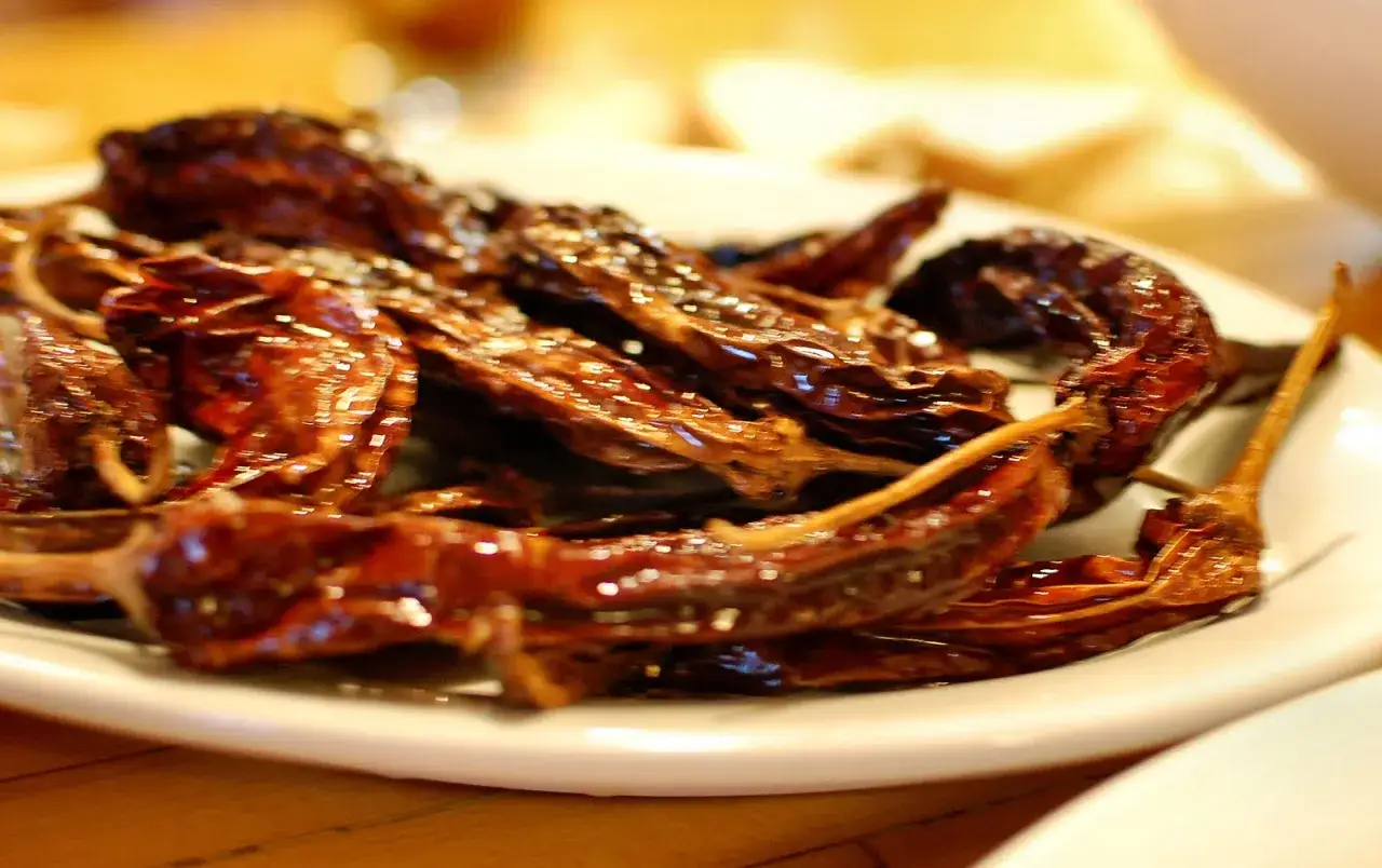 Get ready for a spicy kick! This image shows a pile of dried peperoncino, also known as chili peppers, glistening on a white plate.