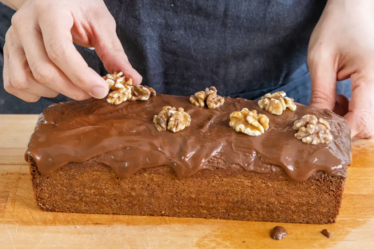 Ein saftiger walnusskuchen ohne mehl, mit Schokoladenglasur und frischen Waln&uuml;ssen dekoriert.