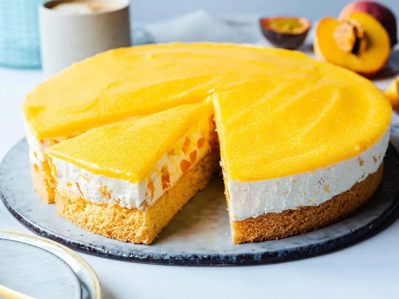 Eine k&ouml;stliche Pfirsich Maracuja Torte mit Biskuitboden, cremiger F&uuml;llung und fruchtigem Topping. Ein St&uuml;ck ist bereits angeschnitten.