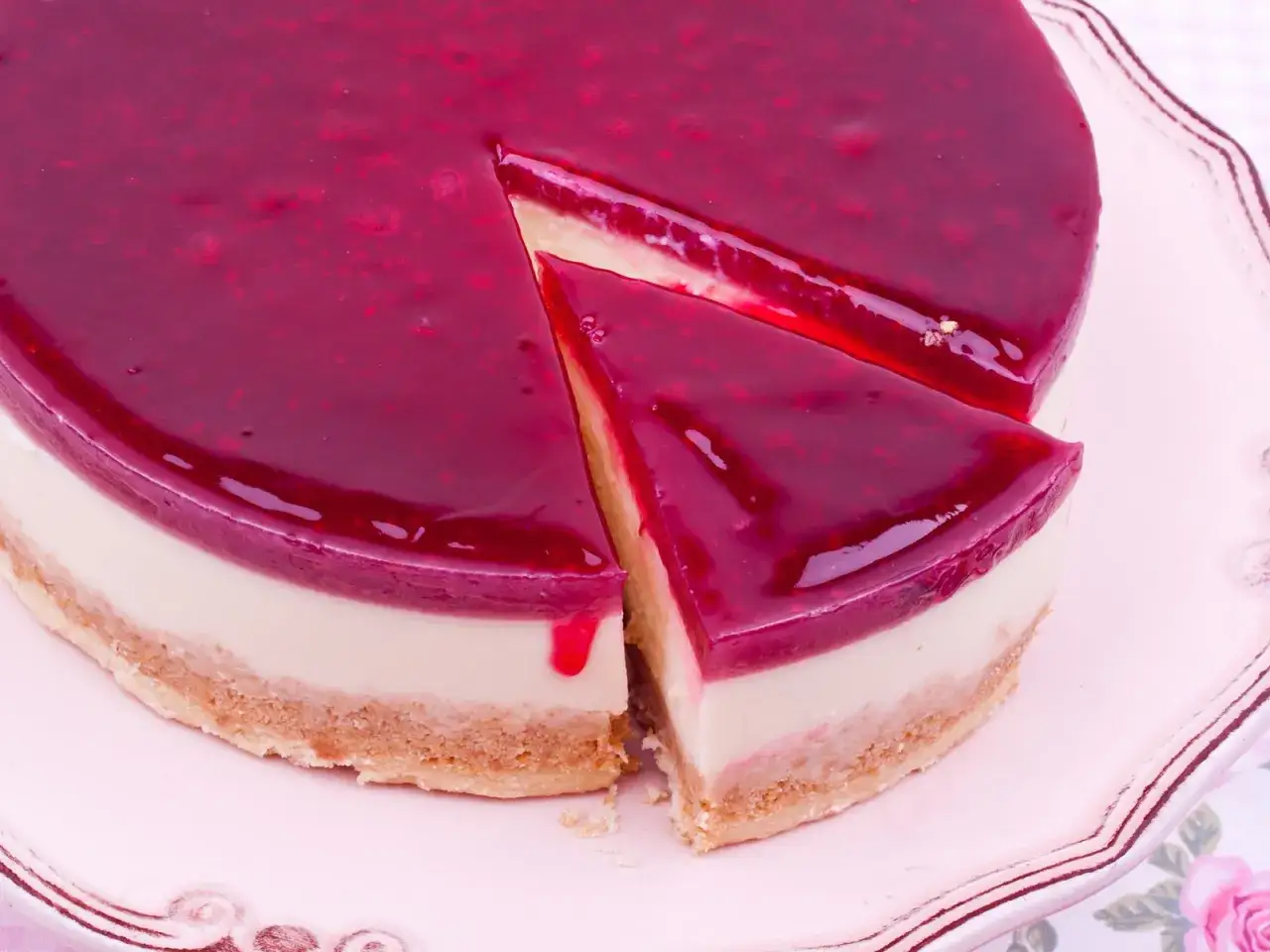 Eine k&ouml;stliche Philadelphia Torte mit leuchtend roter Fruchtsauce, ein St&uuml;ck wurde bereits entnommen.