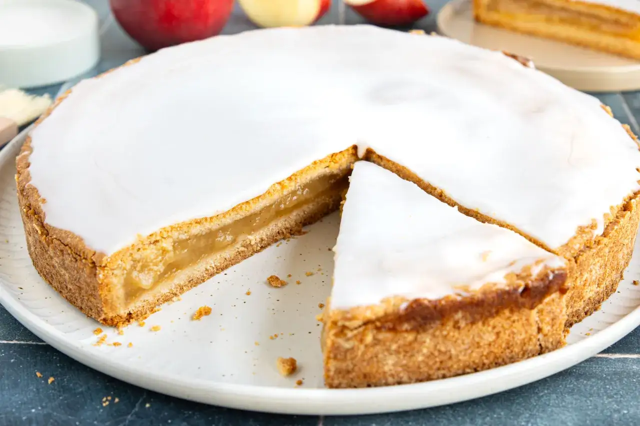 Ein k&ouml;stlicher Apfelkuchen mit einer s&uuml;&szlig;en Apfelmusf&uuml;llung, bedeckt mit glasiertem Zuckerguss. Ein St&uuml;ck fehlt bereits.