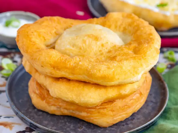 Goldbraune, fluffige Langos stapeln sich auf einem Teller. Ein köstliches Langos Rezept für zu Hause.